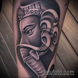 Фото тату крупным планом головы Ганеши на руке, выполненное в технике black and grey. Детализированный рисунок бога с головой слона.