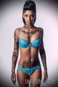 Фото тату на теле: девушка с яркими татуировками оленя на груди и цветами на руках. Красочный рисунок татуировки в стиле реализм.