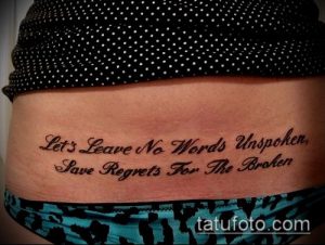 Фото тату на животе: черная надпись "Let's Leave No Words Unspoken, Save Regrets For The Broken". Элегантный рисунок татуировки с красивым шрифтом.