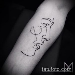 Фото минималистичной татуировки на руке, изображающей лицо, нарисованное одной непрерывной линией. Современный и стильный дизайн татуировки.