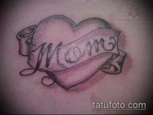 Фото тату: нежное сердце с надписью 'MOM', выполненное в пастельных тонах, создающее мягкий и романтичный образ.