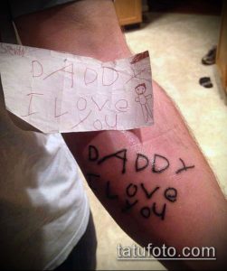 Фото тату на руке: надпись 'Daddy I love you', имитирующая детский рисунок. Черно-белая татуировка, выполненная в наивном стиле.