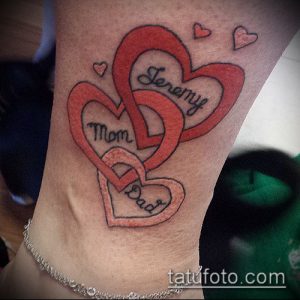 Фото тату на ноге с изображением трех переплетенных сердец с надписями 'Mom', 'Dad' и 'Jeremy'. Рисунок выполнен в красных тонах с черными контурами.