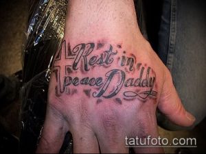 Фото тату надписи 'Rest in Peace Daddy' черным цветом на руке, с изображением креста. Память об отце, траурная татуировка.