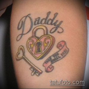 Фото татуировки на предплечье с надписью 'Daddy', изображением сердца-замка, ключа и ленты с надписью. Яркий и красочный рисунок татуировки.