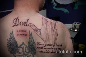 Фото тату на спине и плече: рука, держащая, надпись 'Dad' и даты рождения. Черно-серый рисунок татуировки с надписью и крыльями.