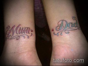Фото тату с надписями 'Mum' и 'Dad' на запястьях, выполненные в нежных розовых и голубых тонах с добавлением небольшого сердечка.