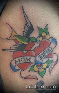 Фото тату в стиле олд скул с изображением ласточки, сердца и надписи 'Mom & Dad'. Традиционный рисунок татуировки с яркими цветами.