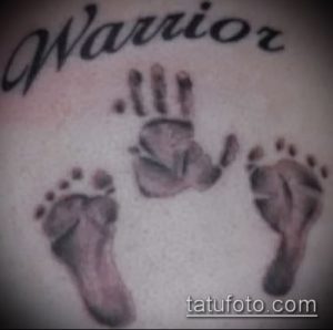 Фото тату с отпечатками детских ладошек и стоп, надписью 'Warrior' в серо-черных тонах, выполненное на коже.