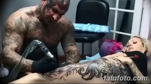 Фото процесса нанесения татуировки: мастер с татуировками на теле работает над рисунком на руке клиентки в тату-салоне.