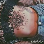 Фото тату мандалы на боку женщины. Детализированный рисунок в стиле дотворк с использованием черных чернил и нежных розовых оттенков.