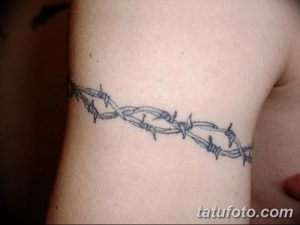 Фото тату колючей проволоки, обвивающей запястье. Рисунок выполнен в черно-серых тонах, с четкой прорисовкой деталей.