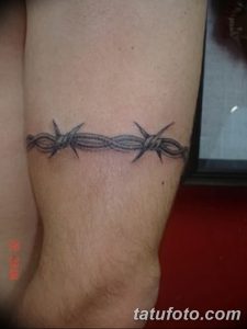Фото тату: простая татуировка колючей проволоки, обернутая вокруг запястья. Черный рисунок татуировки, выполненный тонкими линиями.