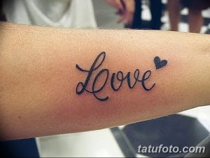 Фото тату надписи "Love" с сердечком на руке. Черно-белый рисунок татуировки, каллиграфический стиль, эскиз тату для девушек.