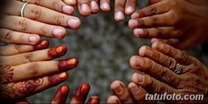 Фото рук, соединенных в круг, украшенных рисунками мехенди в темно-красных тонах, символизирующими единство и общие традиции.