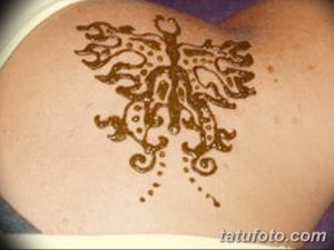 Фото тату мехенди: коричневая бабочка с точками и завитушками на плече, выполненная в технике росписи хной.