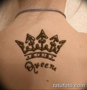 Фото тату хной на спине с изображением короны и надписью 'Queen'. Элегантный и стильный рисунок, выполненный в коричневых тонах.
