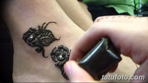 Фото тату мехенди на запястье, с изображением двух роз, украшенных блестками. Детализированный рисунок в коричневых тонах.