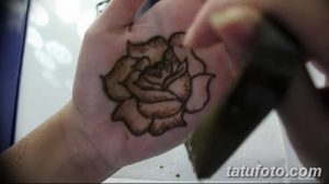 Фото тату мехенди на ладони, с изображением розы, выполненной в коричневых тонах. Детализированный рисунок с тонкими линиями.