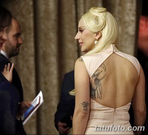 Фотография татуировки на руке Lady Gaga с изображением птицы и цветов. Татуировка выполнена в черно-серых тонах с детализированными элементами.