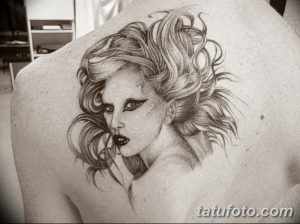 Фотография татуировки с реалистичным портретом Lady Gaga на спине. Татуировка выполнена в черно-серых тонах с высокой детализацией и выразительным взглядом.