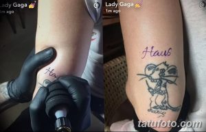 Фото тату Snoopy с надписью 'Haus' на руке Lady Gaga, сделанное в минималистичном стиле. Небольшой рисунок татуировки, выполненный черными чернилами.