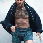 Фотография Тома Харди с множеством татуировок на теле, демонстрирующая его мужественный и стильный вид. Уверенный взгляд актера привлекает внимание.