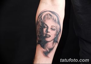 Фотография черно-серой татуировки с изображением Мэрилин Монро на предплечье. Татуировка выполнена в реалистичном стиле с акцентом на детали лица.