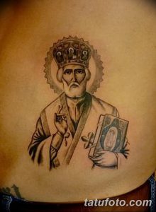 Фото простой татуировки Святого Николая Чудотворца на животе мужчины. Изображение выполнено в черно-серых тонах с минимальным количеством деталей.