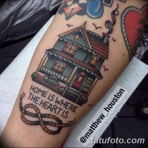 Фото тату: яркий рисунок дома в стиле олд скул на предплечье с надписью 'Home is where the heart is'.