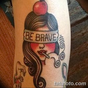 Фото тату на руке: девушка с повязкой 'Be Brave' и красным яблоком, выполненное в традиционном стиле.