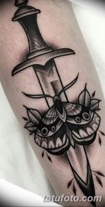 Фото тату на руке в стиле blackwork с изображением кинжала, пронзенного мотыльком. Черно-белый рисунок татуировки с высокой детализацией.