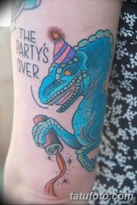 Фото татуировки велоцираптора в мультяшном стиле с надписью 'The Party's Over' и бокалом. Яркие цвета и игривый дизайн.