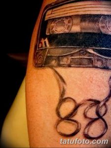 Фото тату кассеты на плече в стиле реализм. Детализированный рисунок с использованием черных и серых оттенков. Идеально для любителей ретро-музыки.