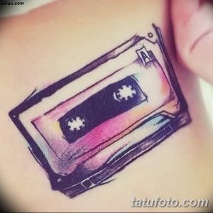 Фотография акварельной татуировки на коже с изображением аудиокассеты, выполненной в нежных розовых, голубых и фиолетовых тонах.