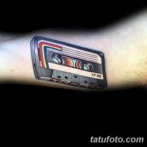 Фото тату кассеты на предплечье, выполненное в стиле old school с яркими цветами. Ностальгический рисунок татуировки для меломанов.