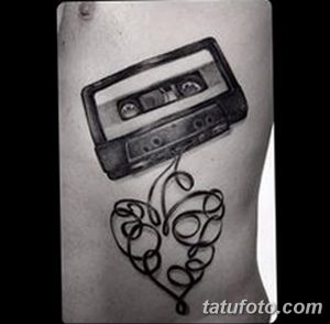 Фото тату кассеты и сердца на боку, выполненное в технике blackwork. Минималистичный рисунок татуировки, символизирующий любовь к музыке.