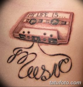 Фото тату на руке: изображение кассеты с надписью "MY LIFE IS MUSIC", выполненное в черно-серых тонах с использованием теней и бликов.