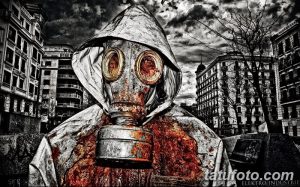 Фото татуировки с изображением человека в капюшоне и противогазе на фоне разрушенного города. Рисунок выполнен в черно-белой гамме с добавлением красных акцентов.