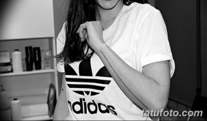 Фото тату: стилизованный логотип Adidas, выполненный в виде тонкой линии на руке девушки. Современный и минималистичный рисунок.
