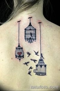 Фото тату: Татуировка на спине с изображением нескольких клеток, из которых вылетают птицы, и одной клетки с сердцем внутри. Черно-белый рисунок.