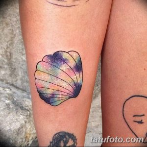 Фото акварельной татуировки ракушки, выполненной в ярких, переливающихся цветах, имитирующих галактику. Нежный и оригинальный дизайн.