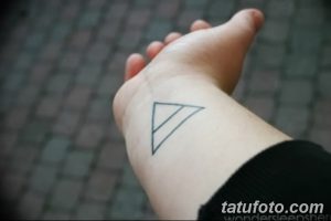 Фото тату: простой черный треугольник на запястье. Минималистичный рисунок татуировки, выполненный тонкими линиями. Идеально для любителей лаконичных эскизов.