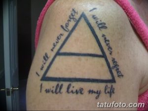 Фото татуировки на плече: черный треугольник с надписью "I will never forget, I will never regret, I will live my life". Эмоциональный рисунок татуировки.