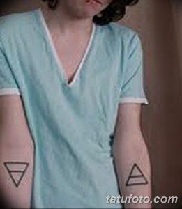 Фото тату: два треугольника, один направлен вверх, другой вниз, на запястьях пары. Простые линии, минималистичный дизайн, символическое значение.