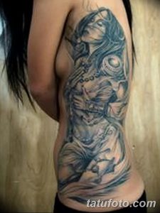 Large black and grey tattoo of a mermaid with flowing hair and intricate scales, covering a woman's side, creating a dramatic and artistic design.