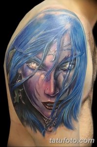 Realistic color tattoo of a woman with striking blue hair and intense eyes, creating a captivating and mysterious portrait.