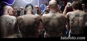 Фотография группы мужчин с татуировками на спине, демонстрирующая разнообразие стилей и сюжетов татуировок.