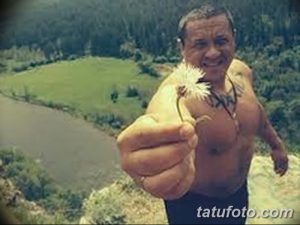 Фотография мужчины с татуировкой на руке, держащего одуванчик. Идеально для поиска идей для тату в природном стиле.
