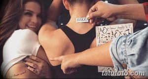 Фото процесса нанесения временной татуировки на спину девушки. Видны руки, наносящие переводную картинку и улыбающаяся девушка рядом.